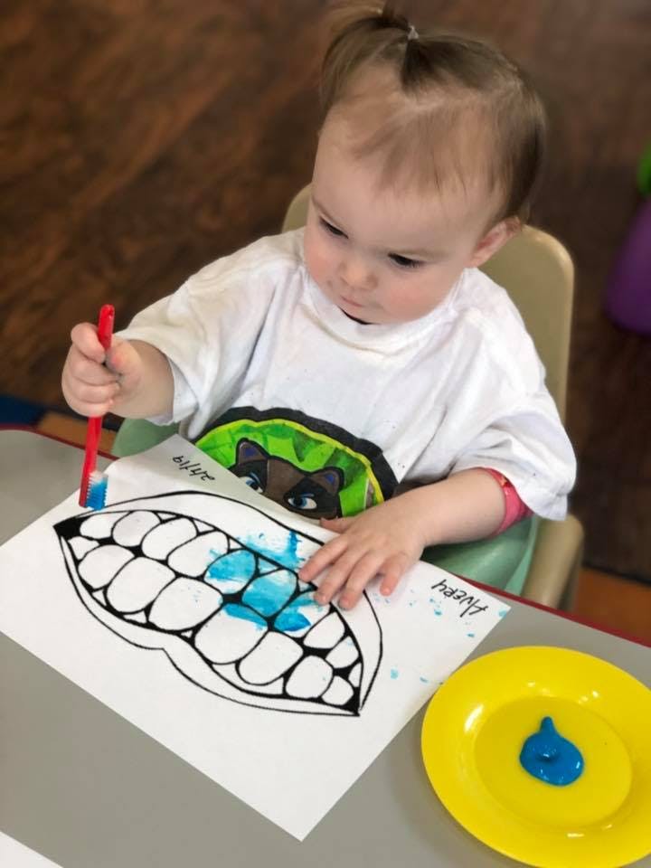 Child painting a drawing of teeth with a paintbrush