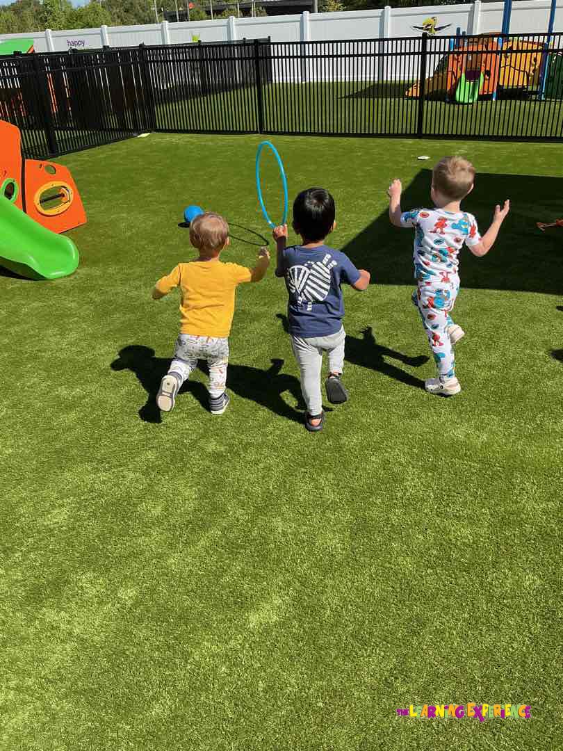 Three children playing on a green turf playground