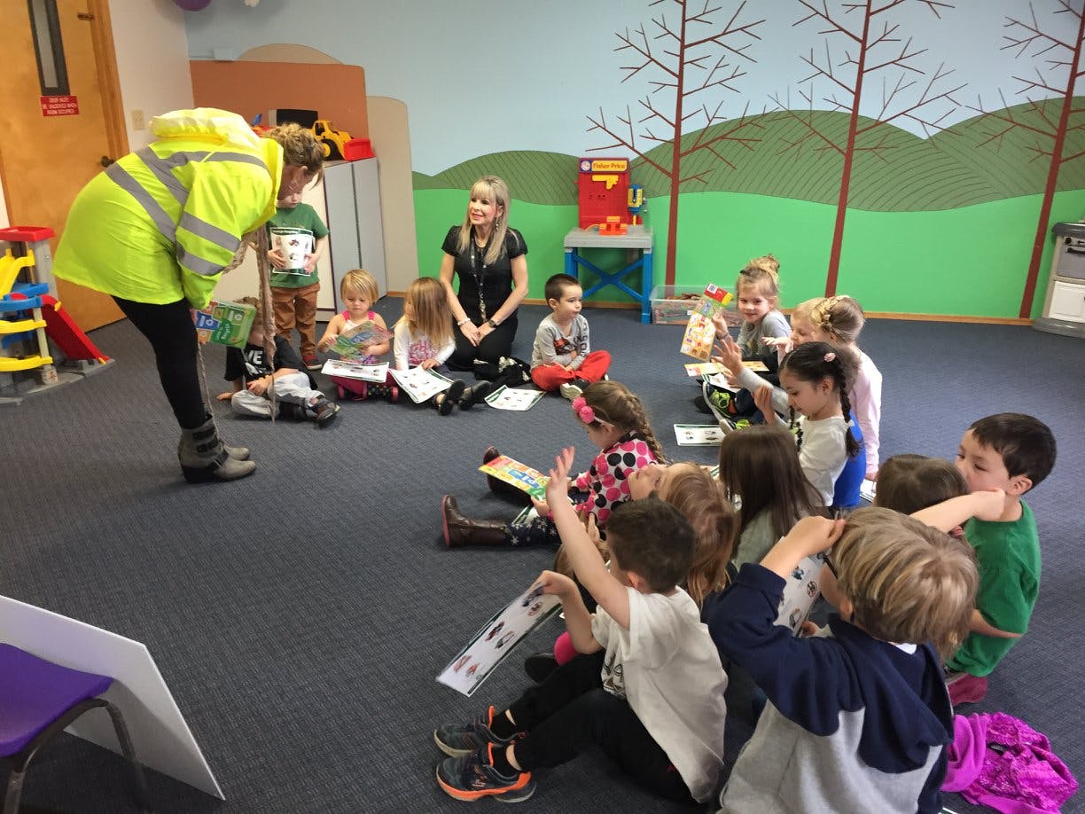 Person in safety vest interacting with children sitting on floor
