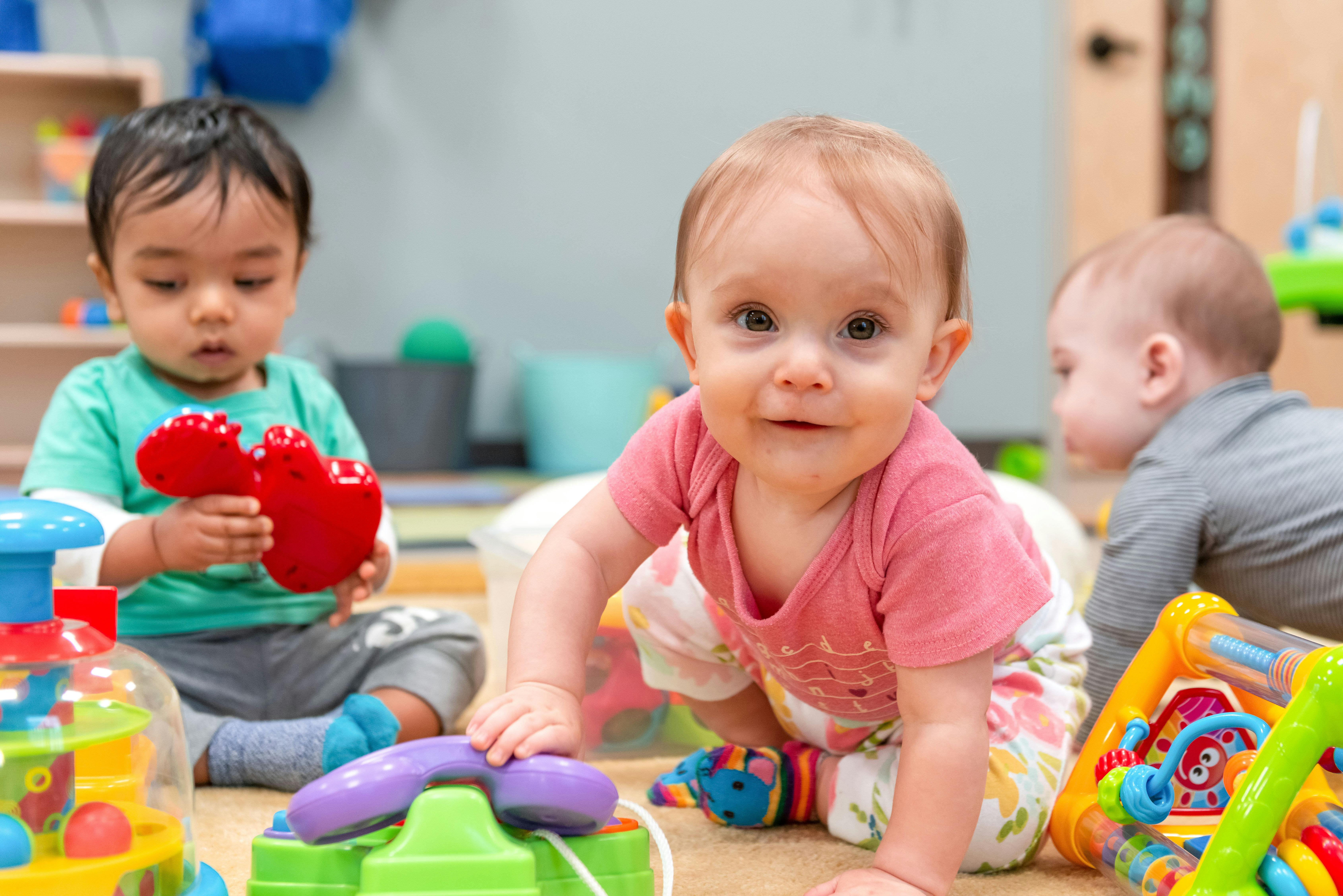 Three babies playing with toys on the floor