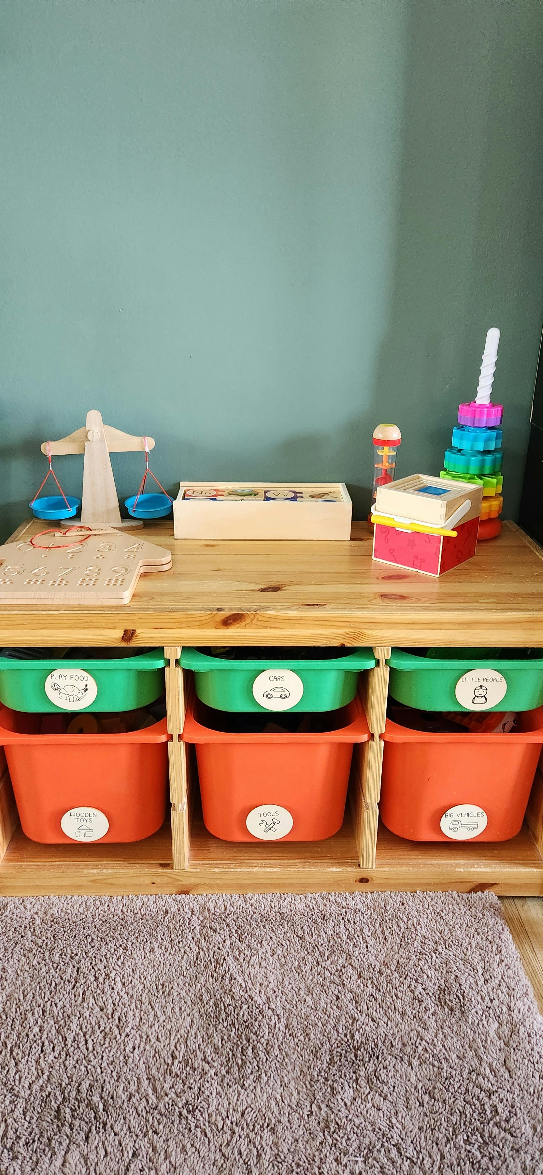 Wooden storage unit with colorful bins and children's toys on top