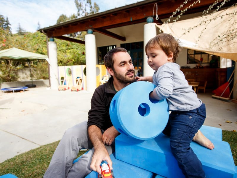 Person and child playing with blue foam blocks outdoors