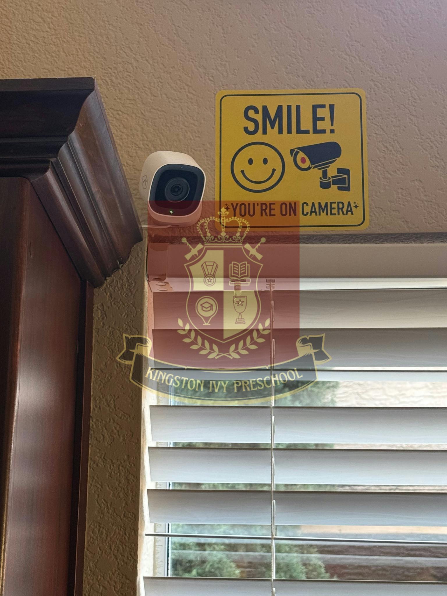 Security camera next to a yellow sign that says "SMILE! YOU'RE ON CAMERA"