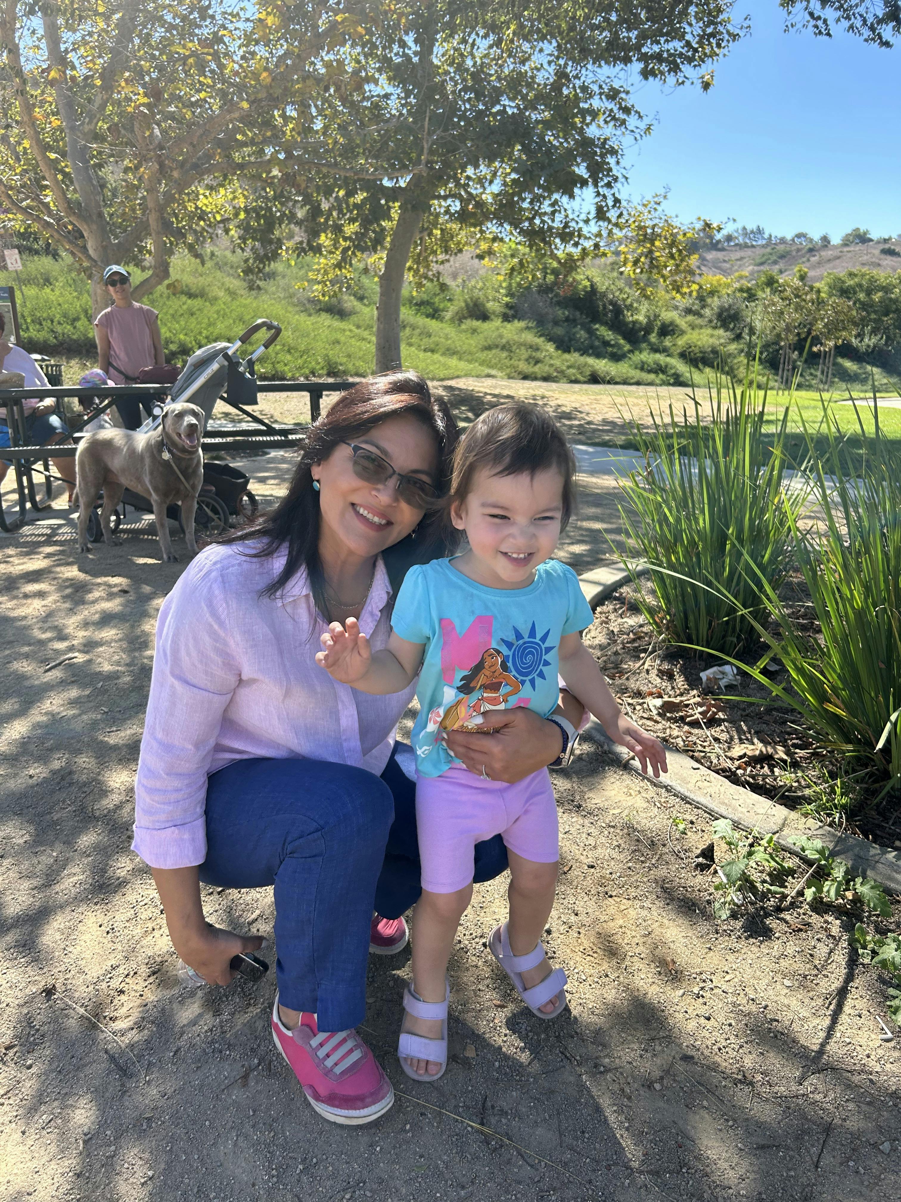 Adult kneeling beside a child at a park