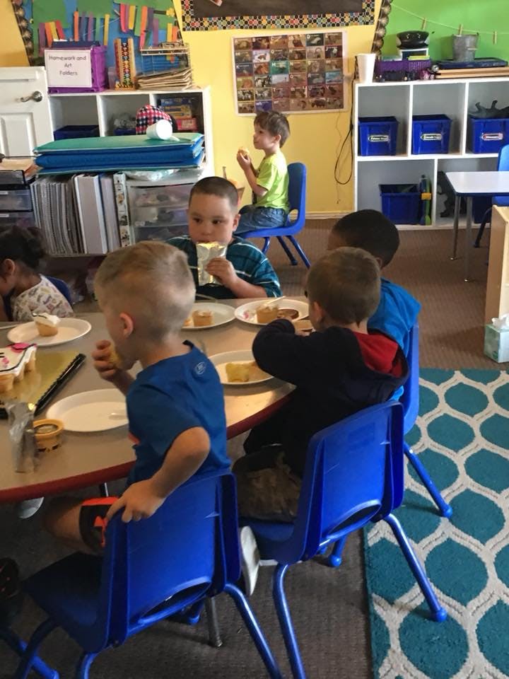 Children eating at a table in a classroom