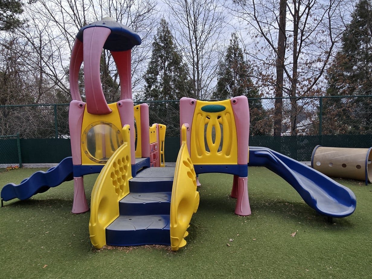 Colorful outdoor playground structure with slides, stairs, and a tunnel