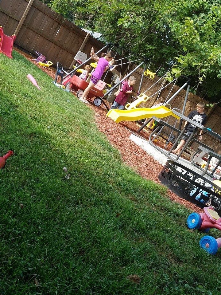 Children playing on a swing set and slide in a backyard