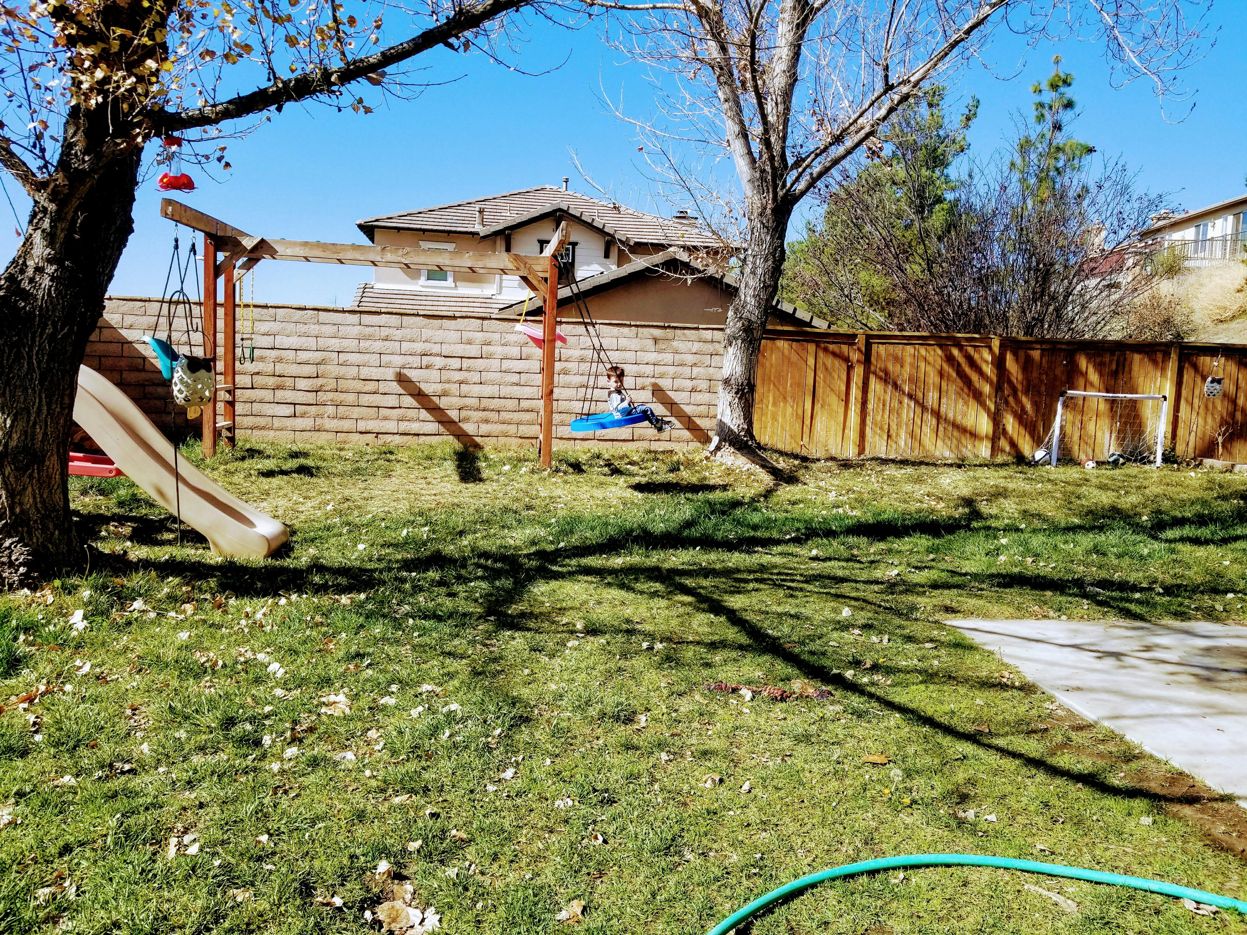 Child on a swing set in a grassy backyard