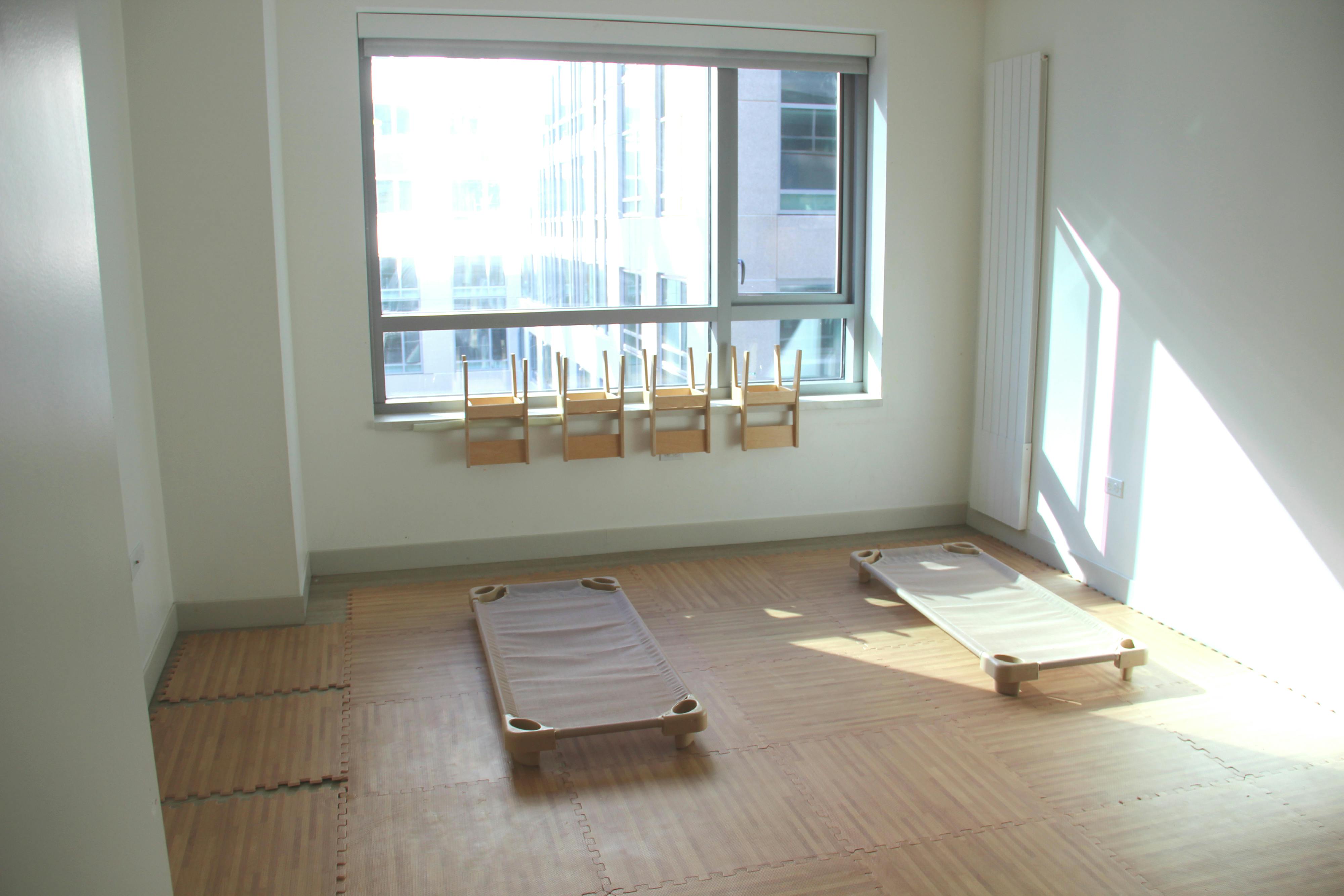 Empty room with two cots on the floor and chairs on a window ledge