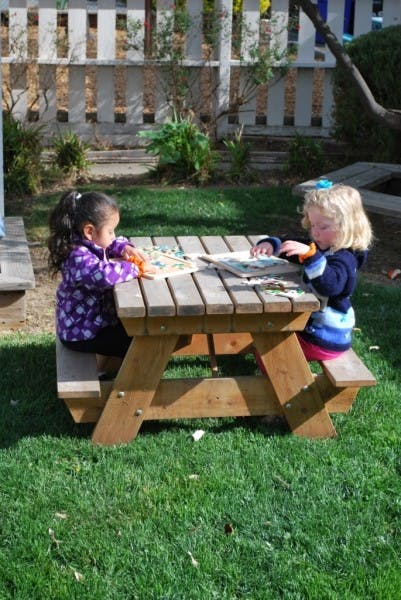 Two children sitting at a picnic table playing with puzzles