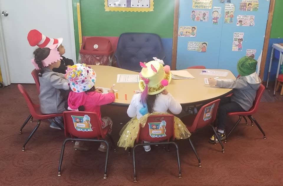 Children wearing hats sitting around a table in a classroom