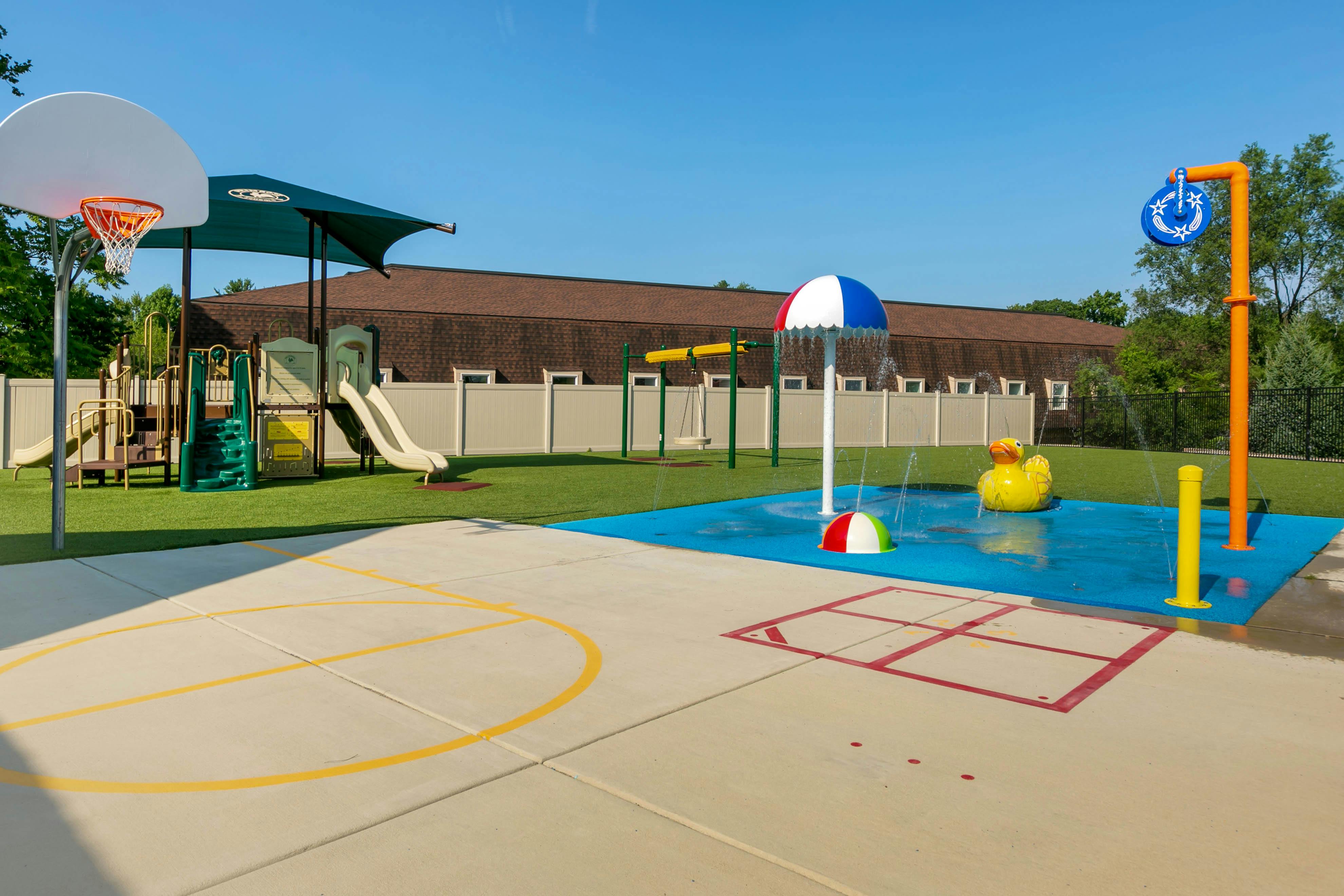 Basketball hoop, playground, and splash pad with a giant duck and water umbrella