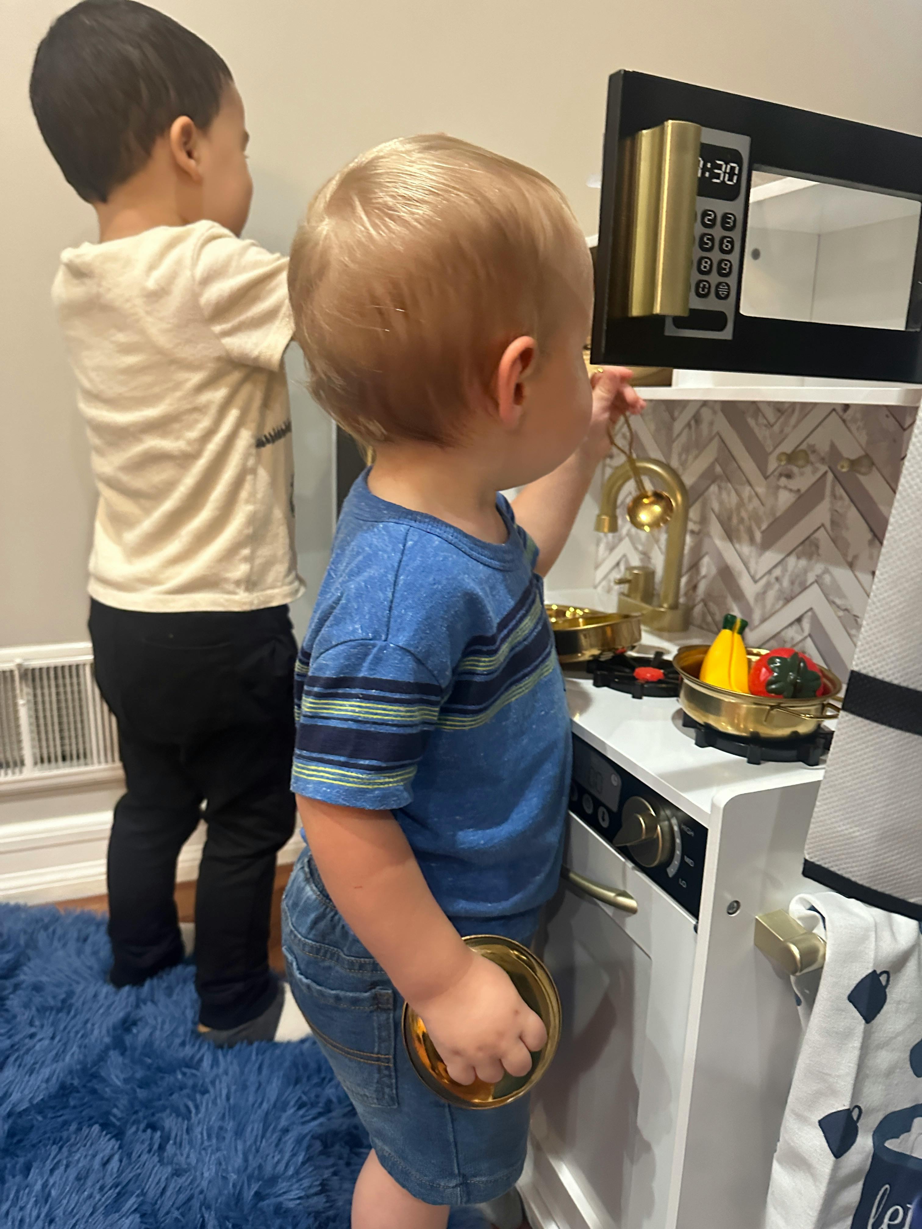 Two children playing with a toy kitchen set