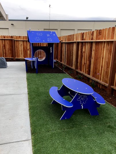 Blue playhouse and picnic table on artificial grass