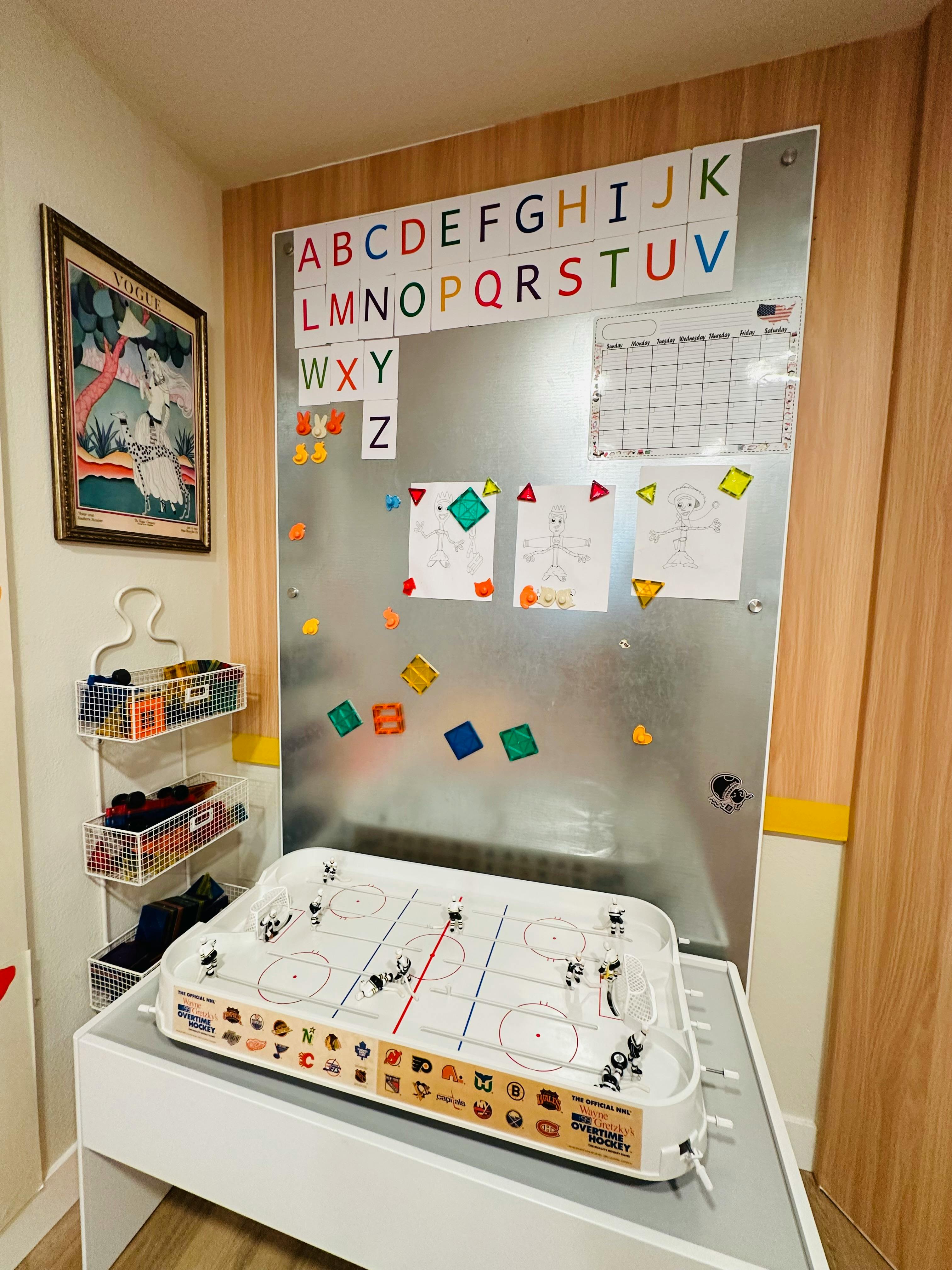 Magnetic board with alphabet letters, papers, and an air hockey table below