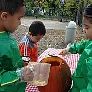 Children carving a pumpkin outdoors