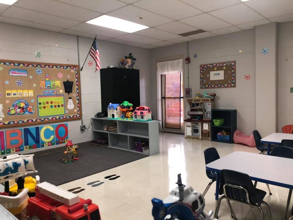 Classroom with bulletin board, play area, and tables