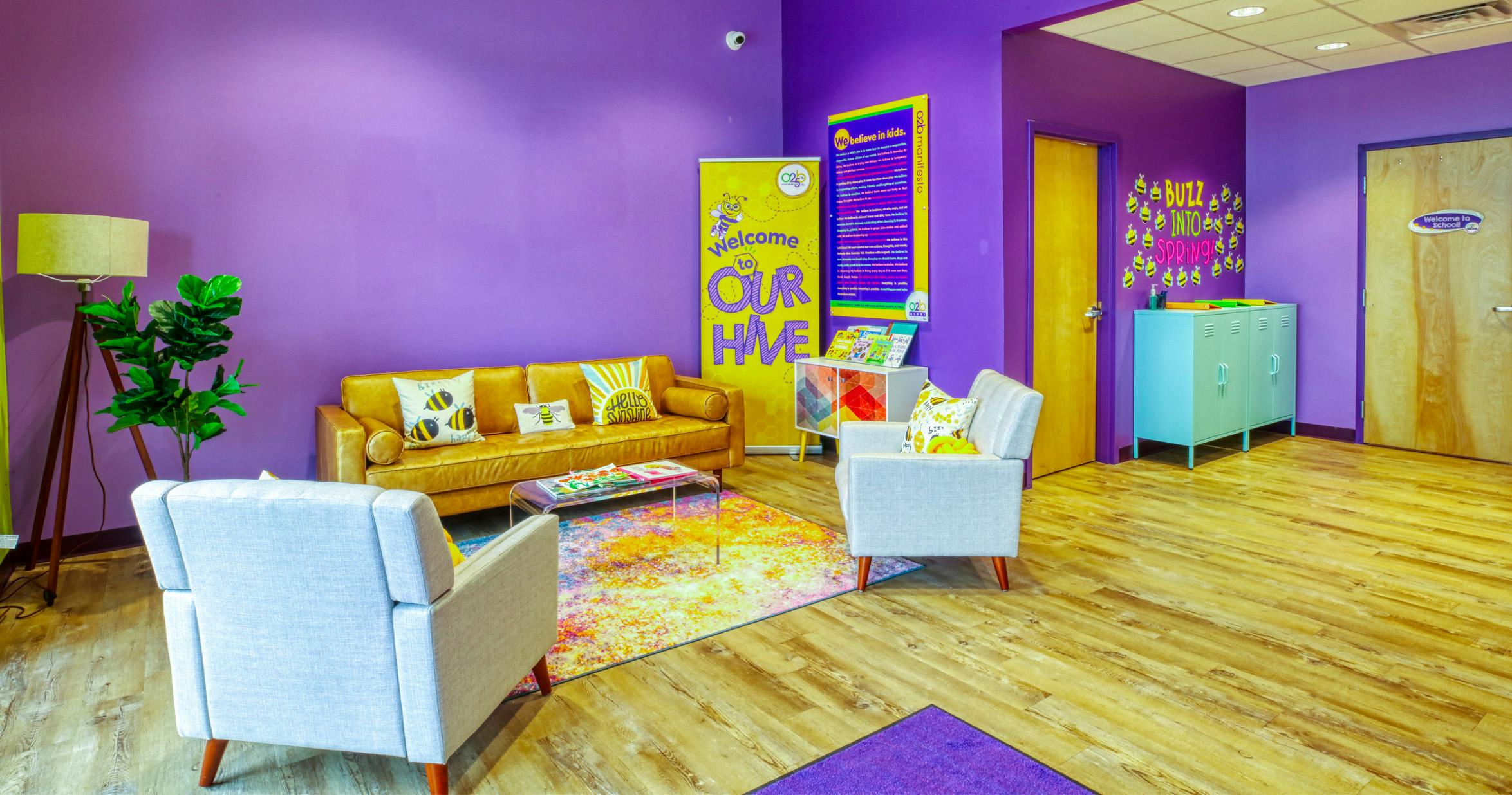 Lounge area with purple walls, yellow couch, two armchairs, and colorful rug