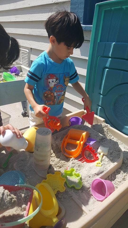 Child playing in a sandbox with sand toys