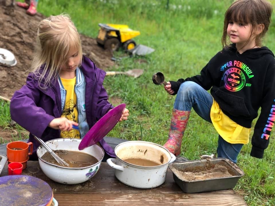 Two children playing with mud and pots outdoors