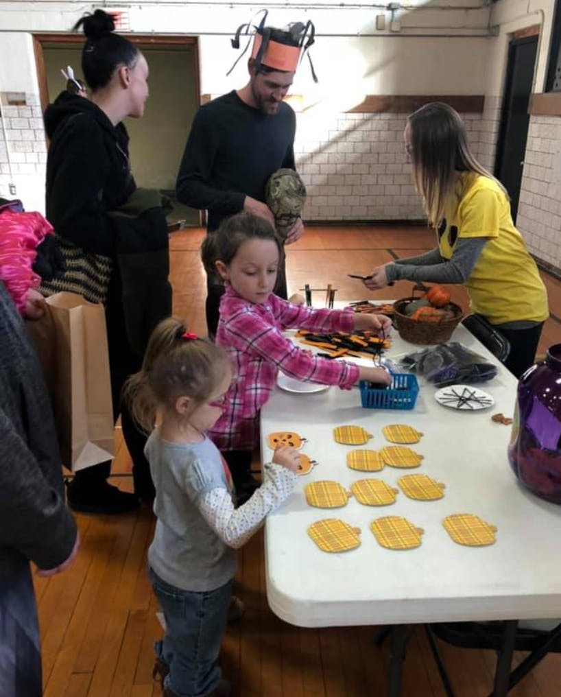 People and children decorating pumpkin cutouts at a table
