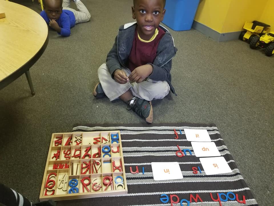 Child sitting on floor with letter tiles and cards