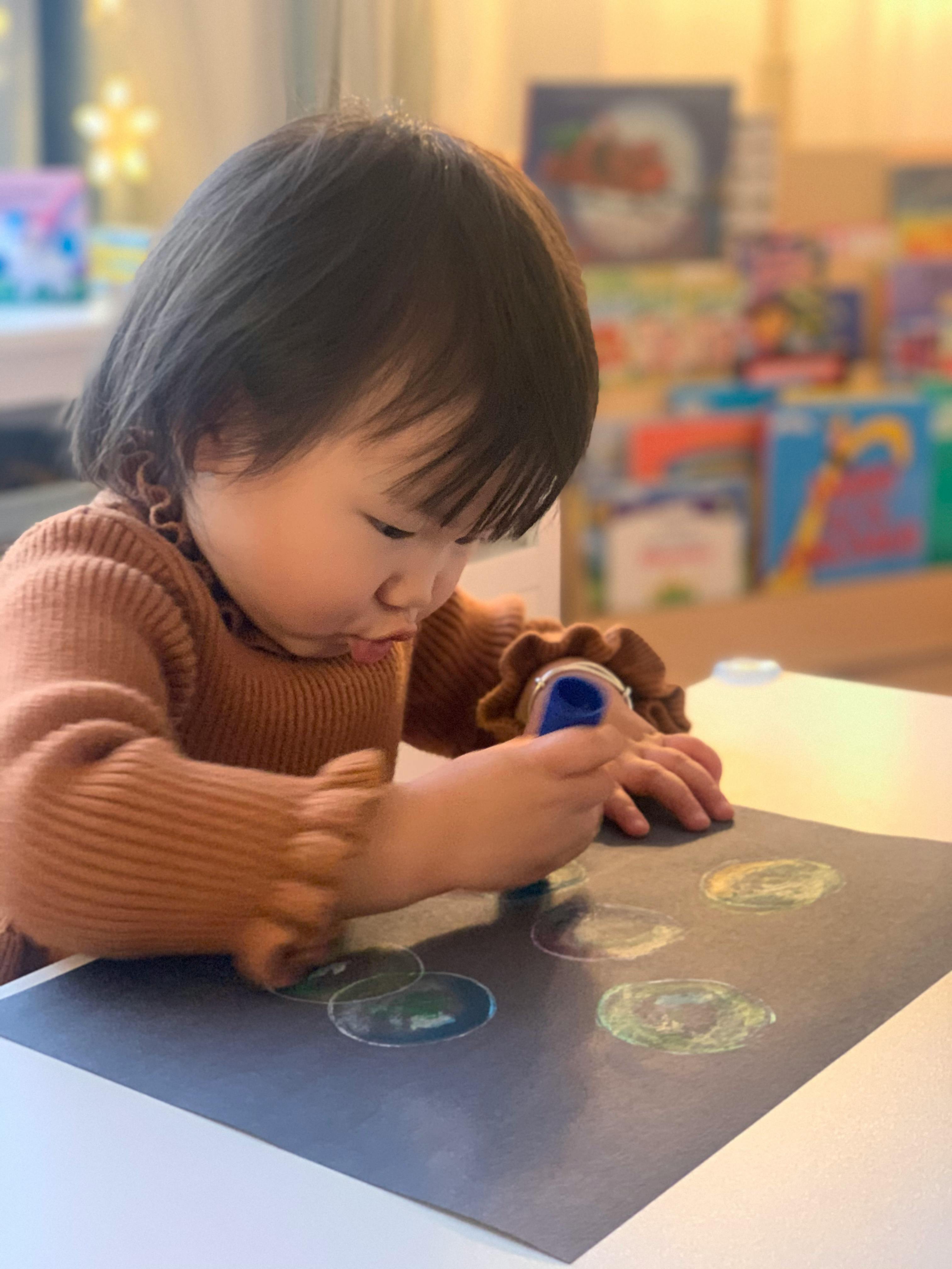 Child drawing on dark paper with a blue marker