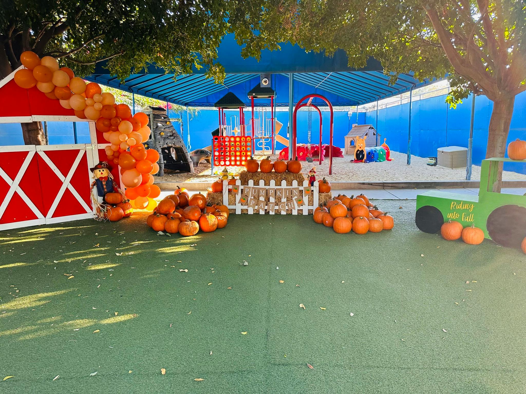 Playground with pumpkins, a red barn, and a green tractor cutout