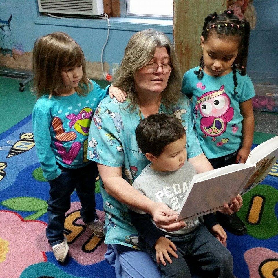 Adult person reading a book to three children
