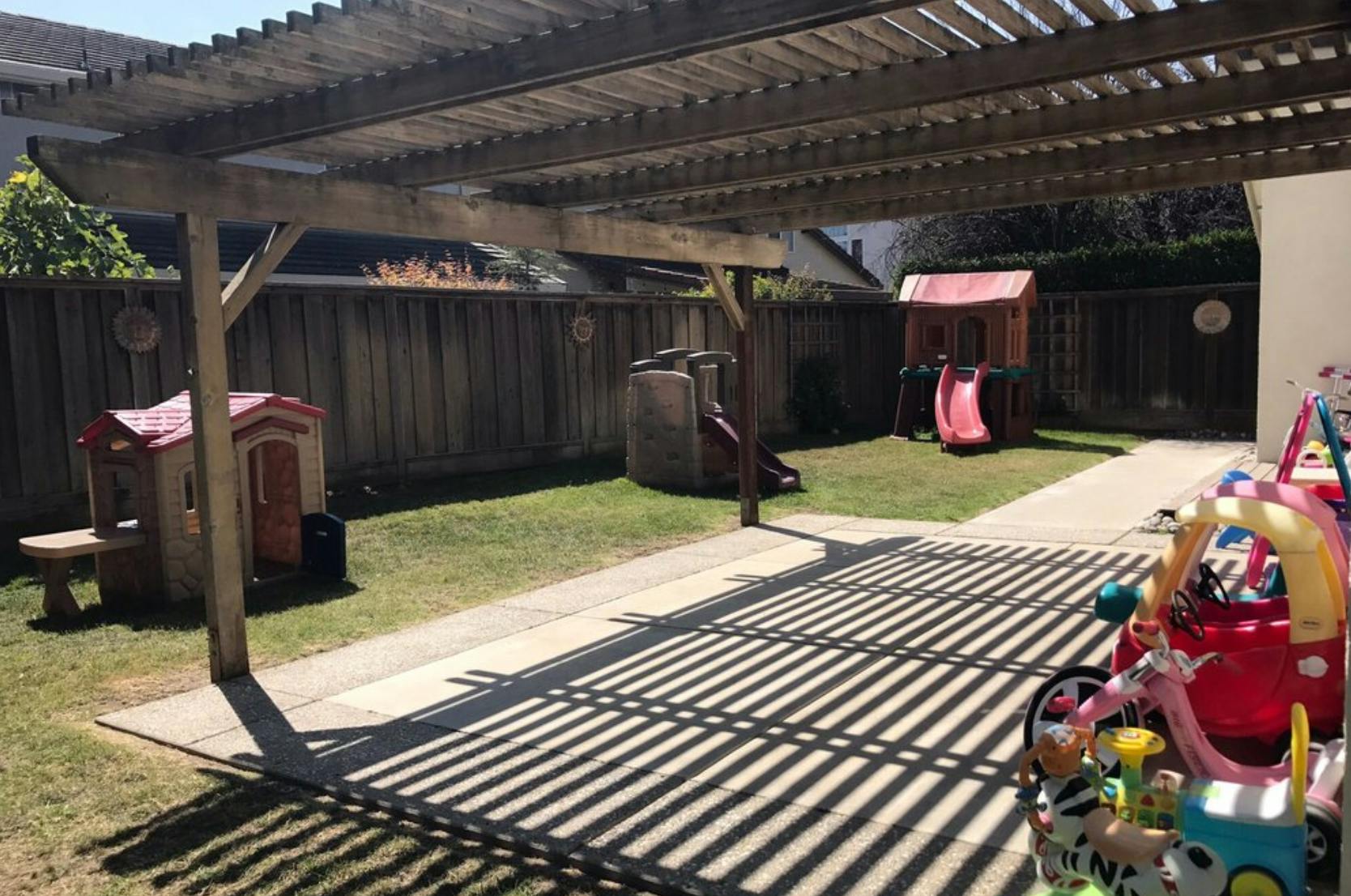 Backyard with a wooden pergola, playhouses, and slides
