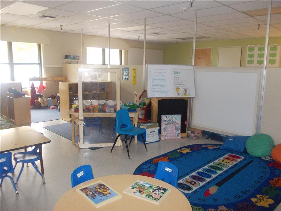 Empty colorful preschool classroom with tables, chairs, and play areas