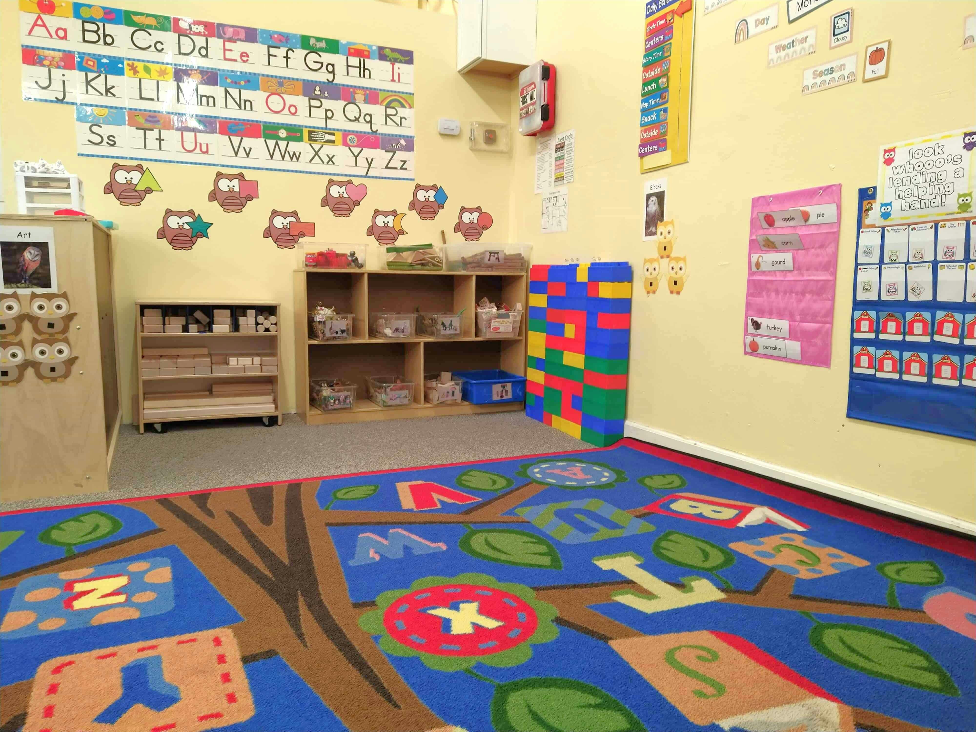 Classroom with alphabet chart, shelves, and colorful rug