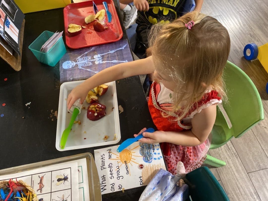 Child playing with food and drawing at a table