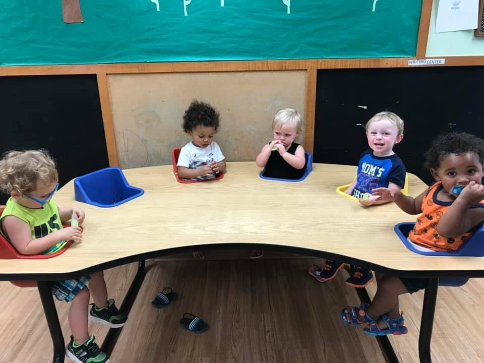 Five children sitting at a curved table in a classroom