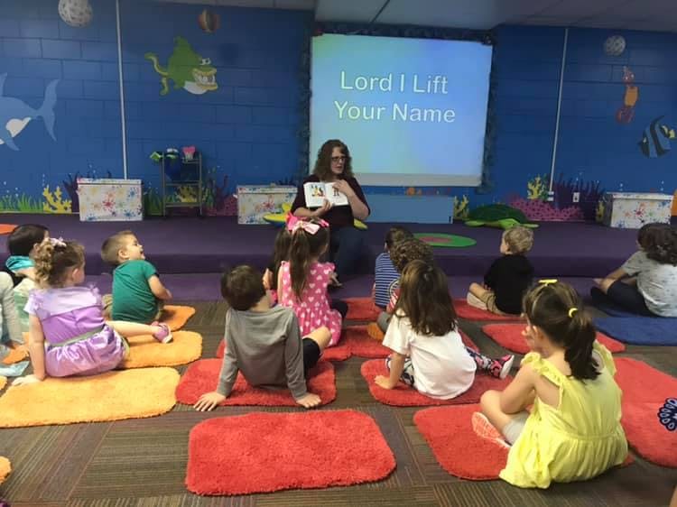 Adult reading to children sitting on mats in a classroom