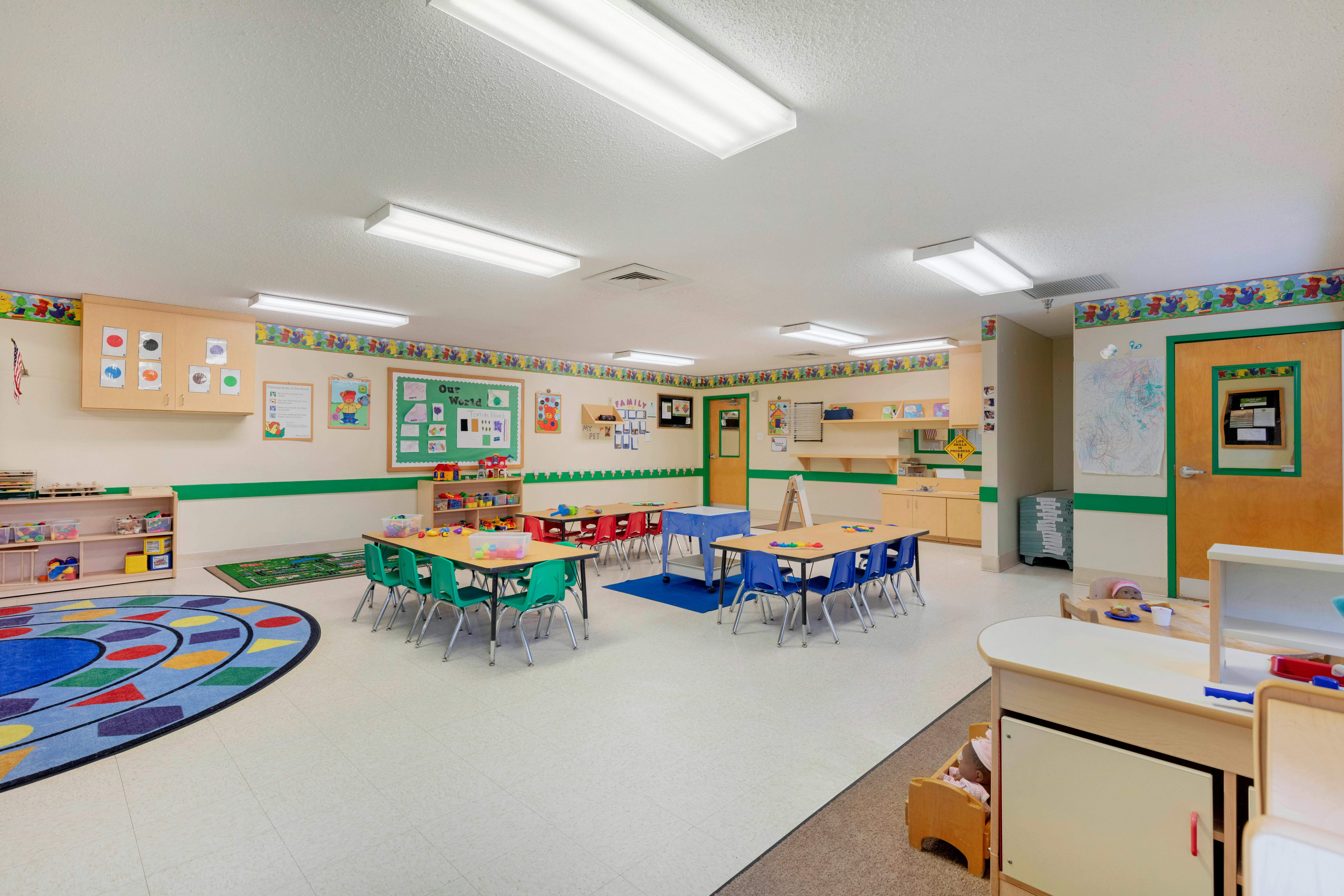 Classroom with child-sized tables and chairs, colorful rugs, and learning materials