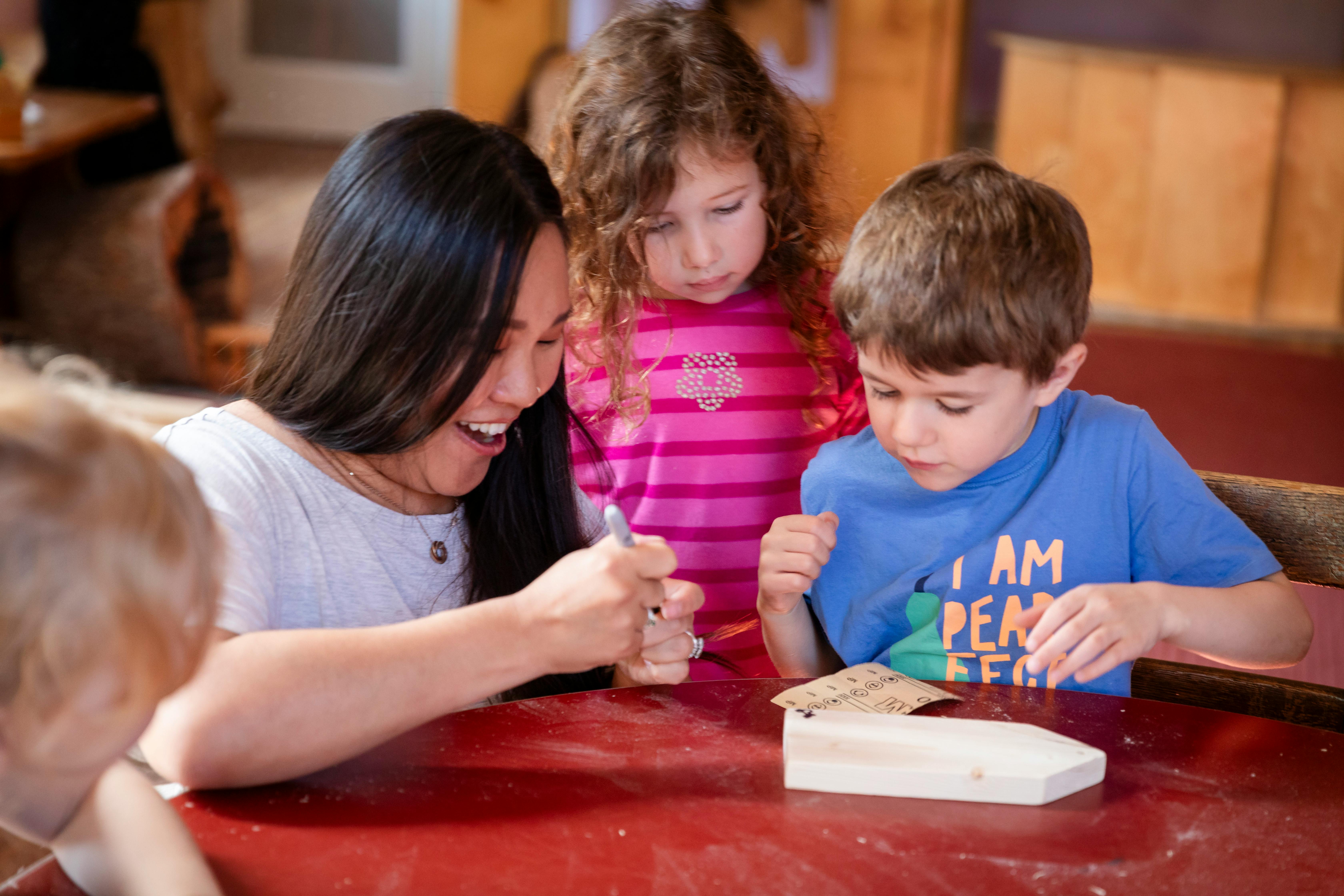 Person and two children working on a craft project at a table