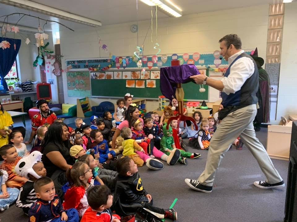 Person performing magic for a group of children in a classroom