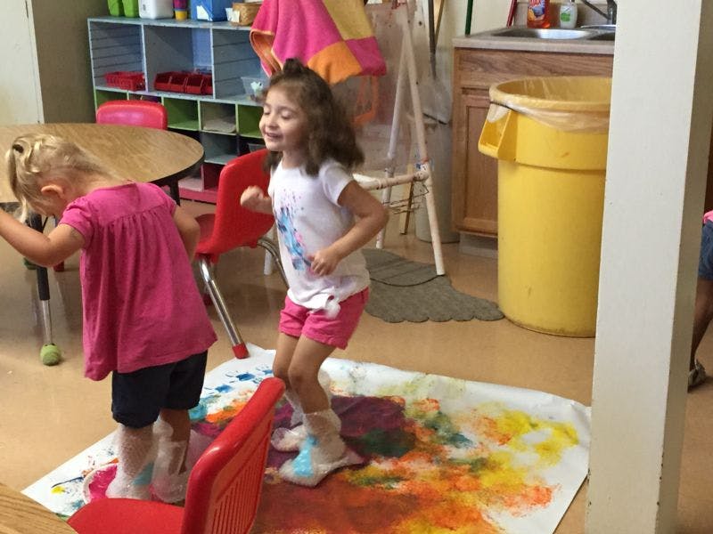 Two children standing on a paint-splattered sheet