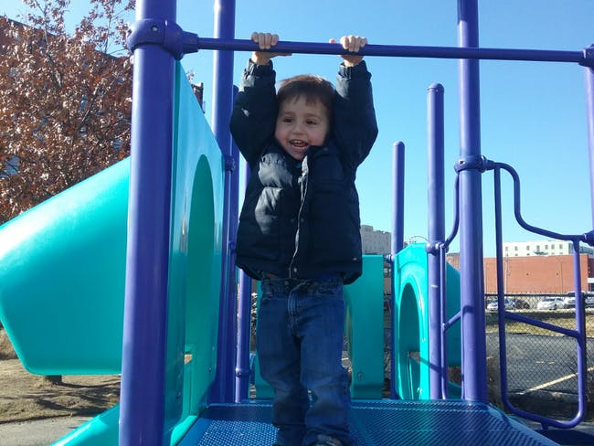 Child hanging from a bar on a playground structure