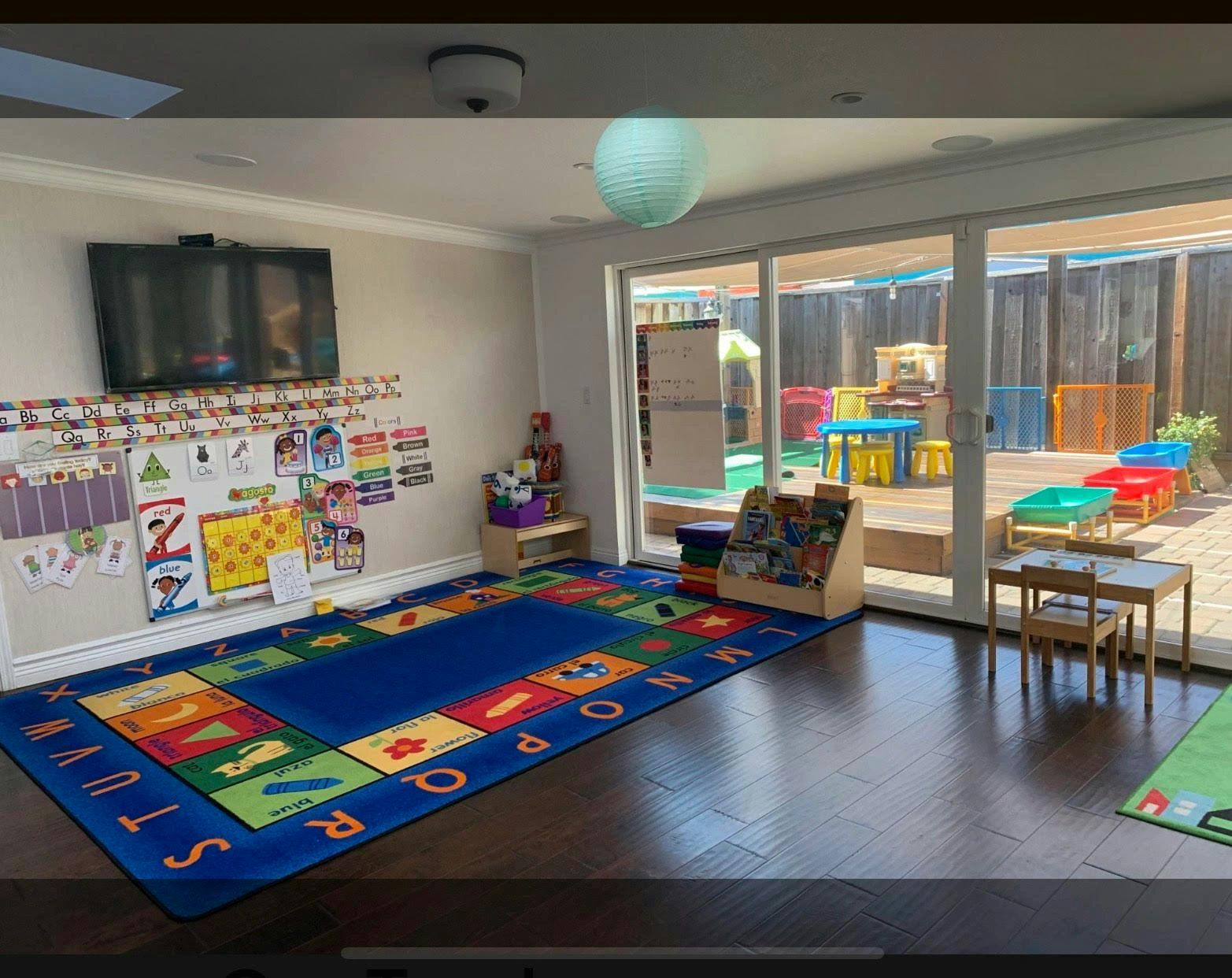 Children's playroom with an alphabet rug and an outdoor play area visible through glass doors