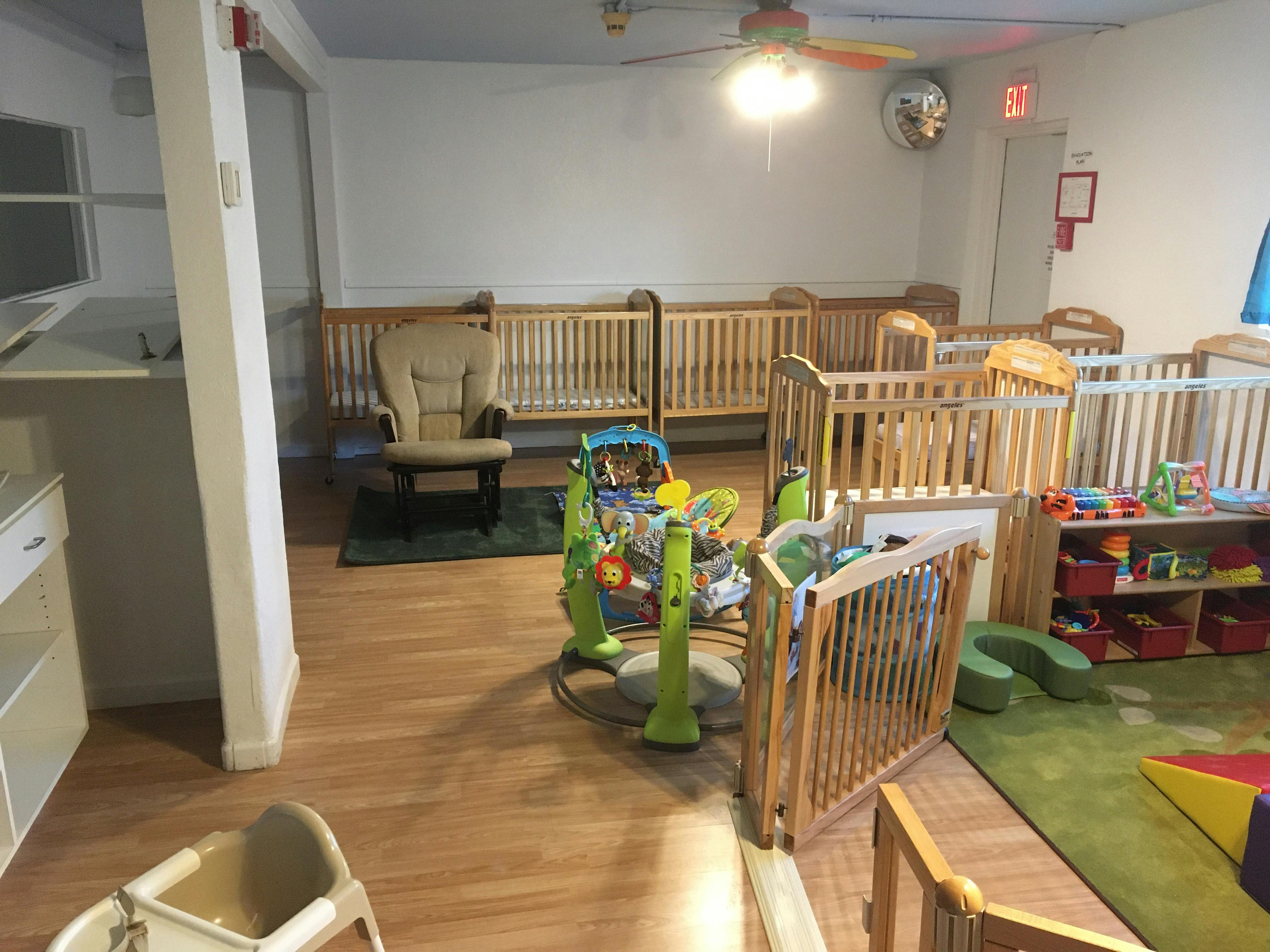 Room with multiple cribs, a baby activity center, and a rocking chair