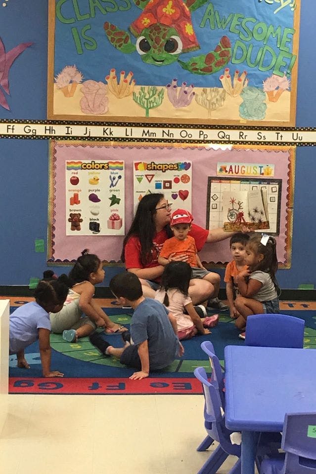 Adult and children sitting on a rug in a classroom