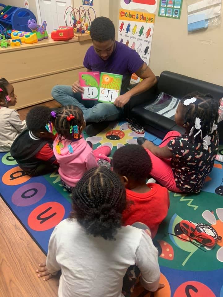 Person reading a book to several children in a classroom