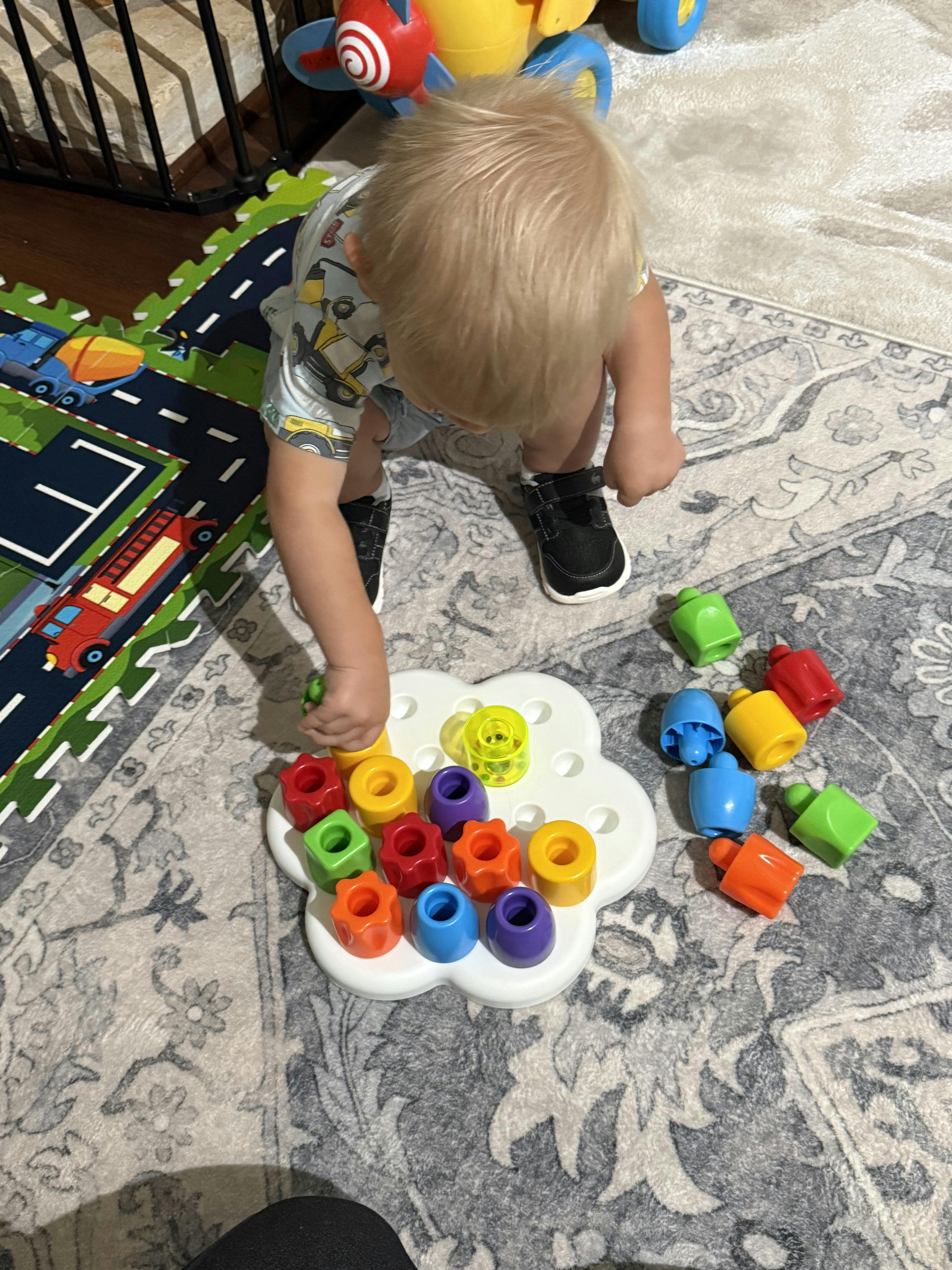 Child placing a colorful plastic peg into a flower shaped board