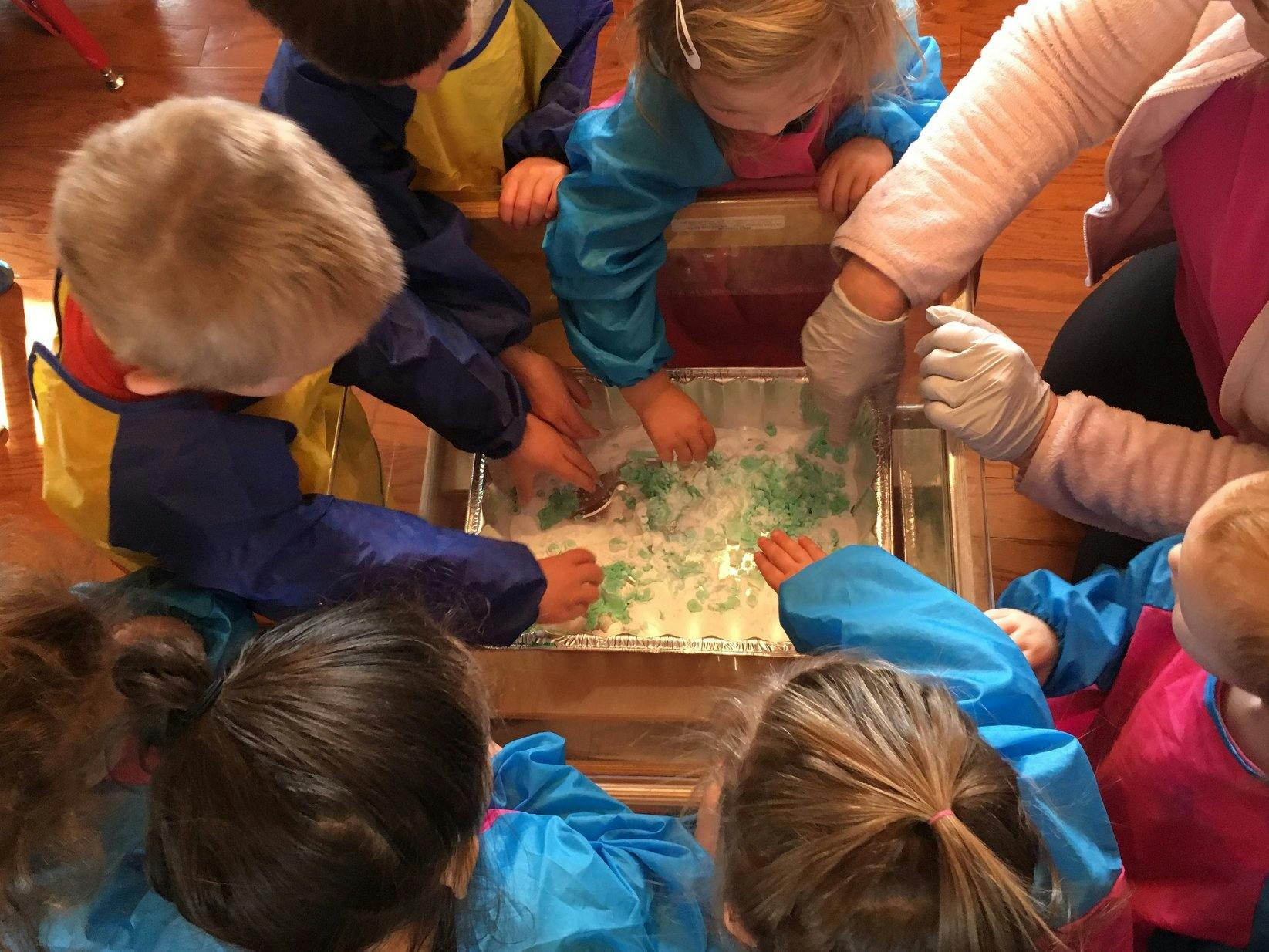 Children and an adult playing with sensory bin materials