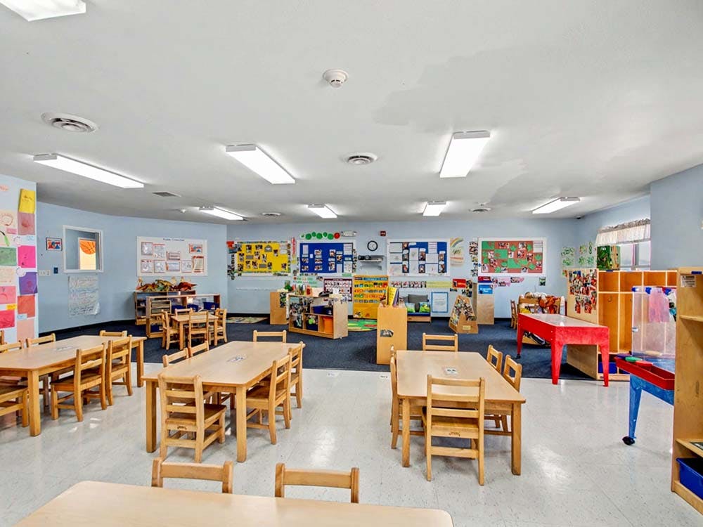 Empty classroom with small wooden tables and chairs