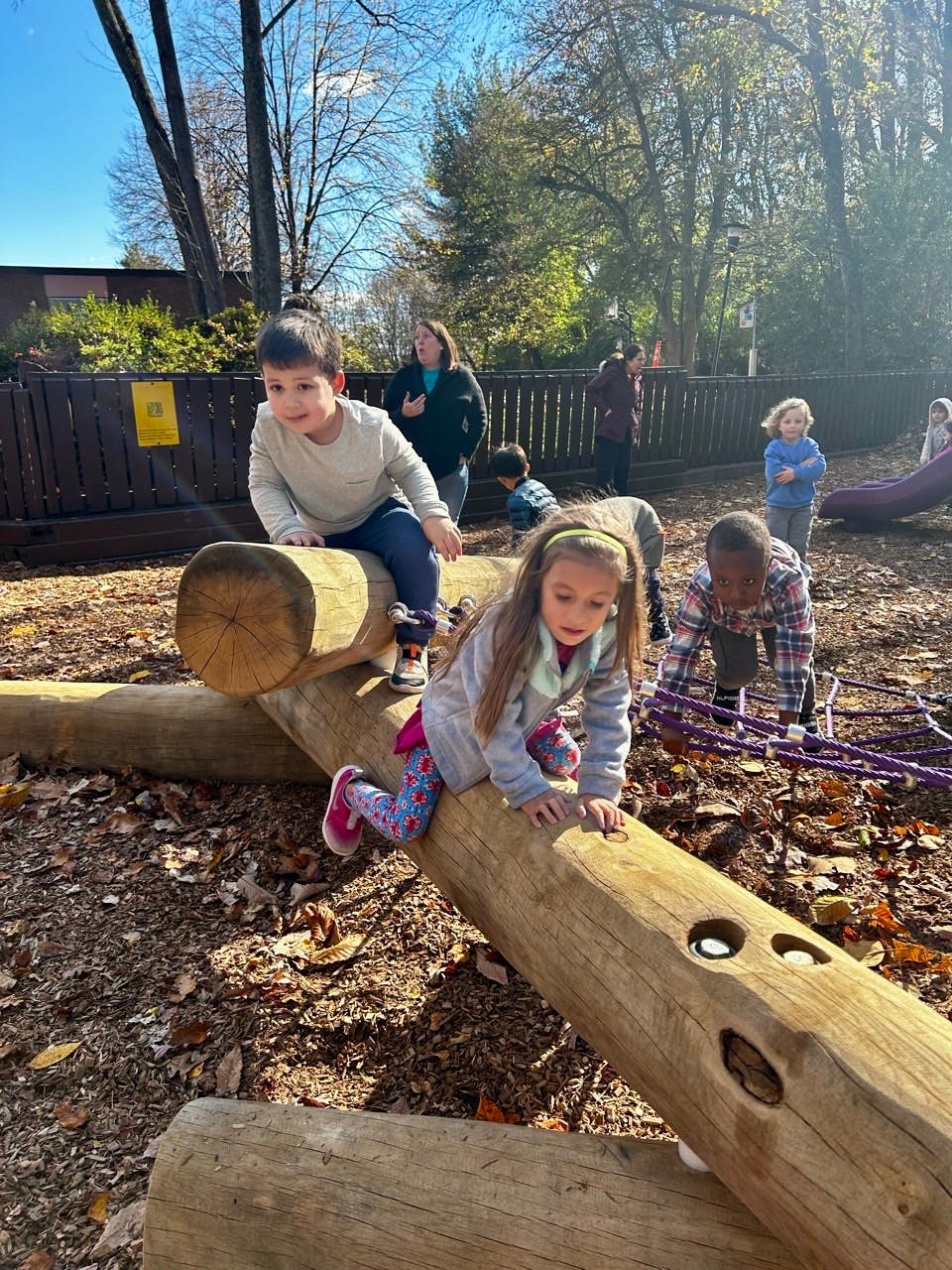 Children playing on wooden logs outdoors