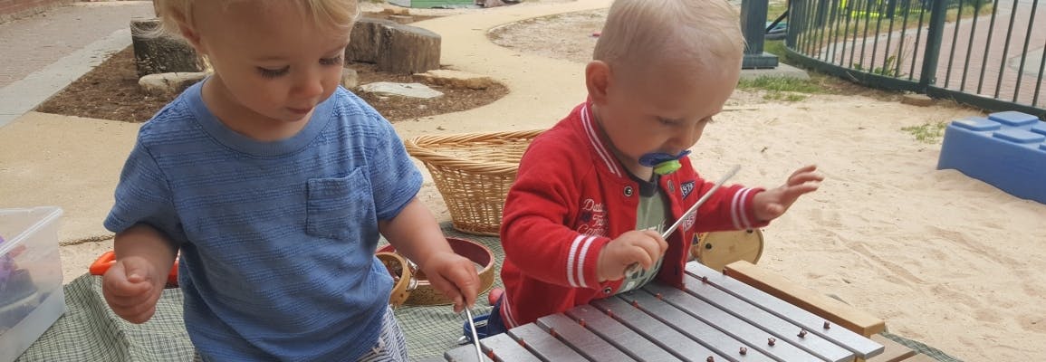 Two children playing with musical instruments outdoors