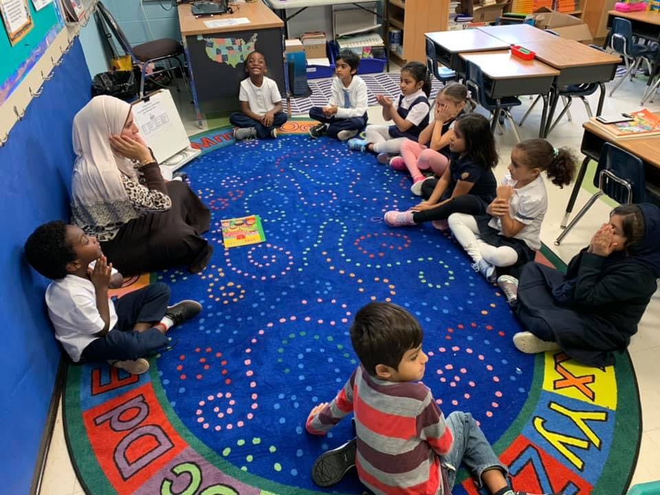 Adult reading to children sitting on a rug in a classroom